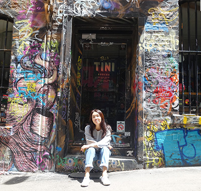 Moah sitting on the steps of a graffitied building.