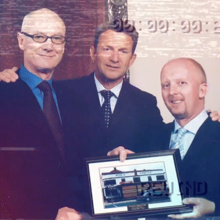 John Grill and two other people holding a framed image of an office.