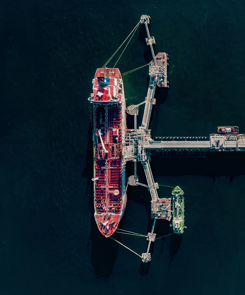 Aerial view of large ship next to an oil storage tanks.