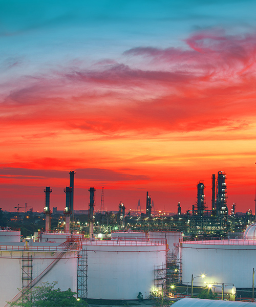 Oil refinery petrochemical plant with a vibrant orange sky.