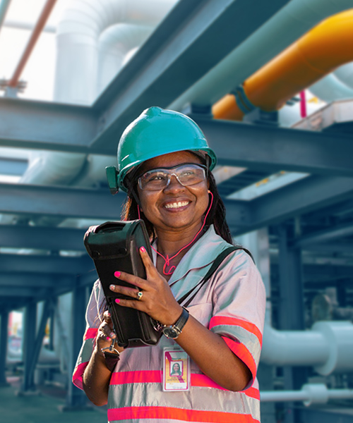 Woman wearing safety helmet holding a transmitter radio at a refinery.