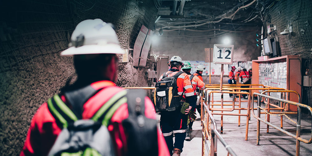Several mine workers wearing PPE walking in Oyu Tolgoi's underground mine.