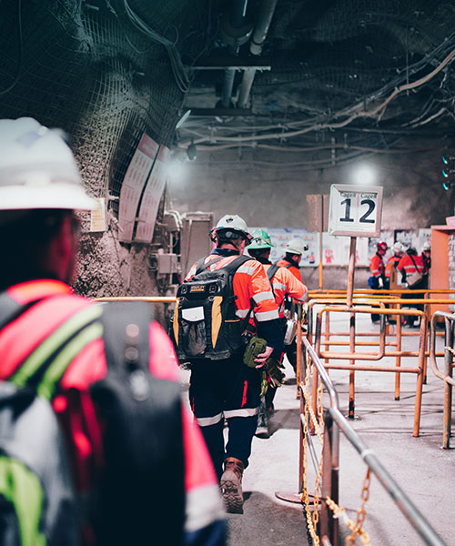 Several mine workers wearing PPE walking in Oyu Tolgoi's underground mine.