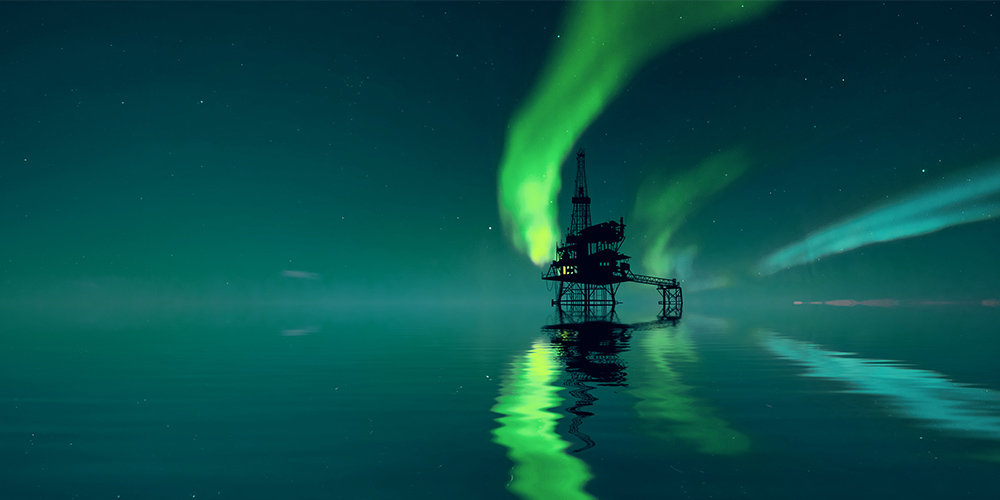 Offshore oil platform in front of the green Northern Lights.